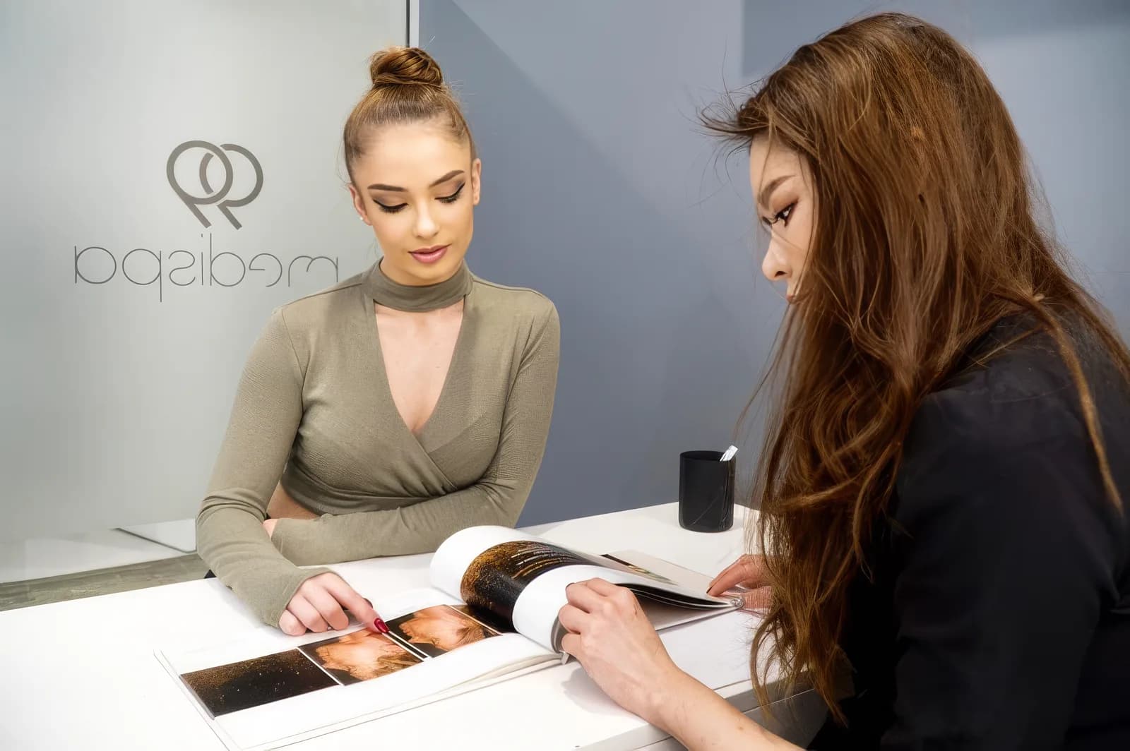 A practitioner talking a client through treatment options at the 99 Medispa consultation desk